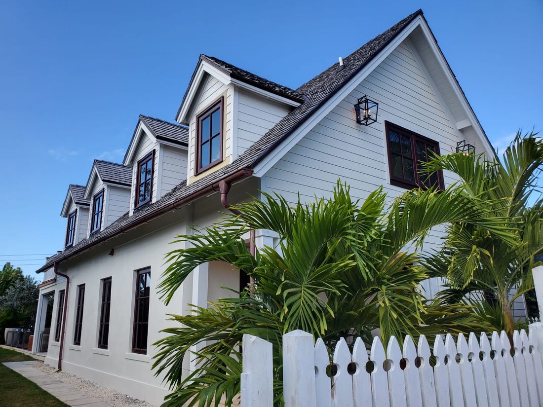 Completed white two storey home with dormer windows and mahogany trim.