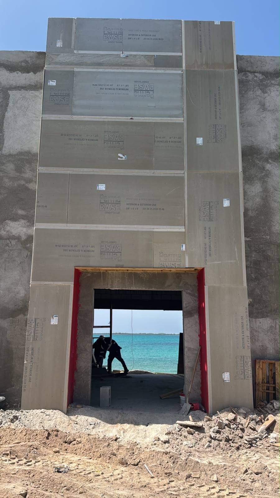 Cement board cladding around a tall opening framing a view of the ocean.