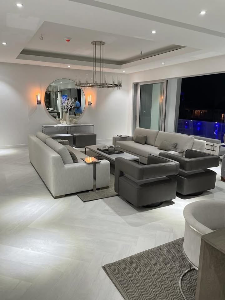 Living room at night under a coffered ceiling with the lit pool visible outside.