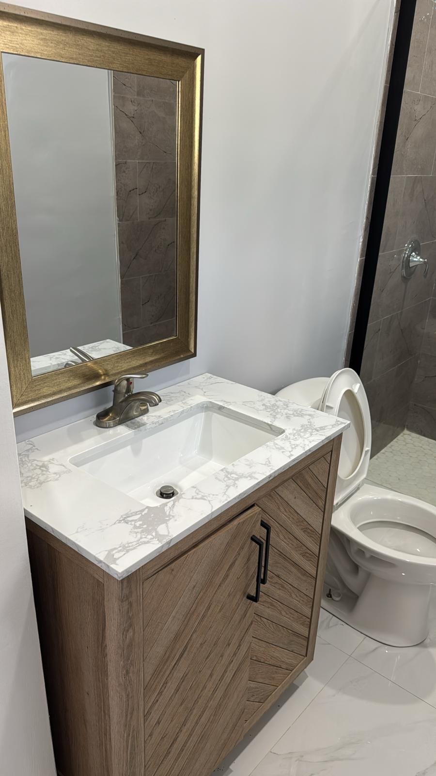 Timber vanity with stone top, framed mirror and undermount basin.